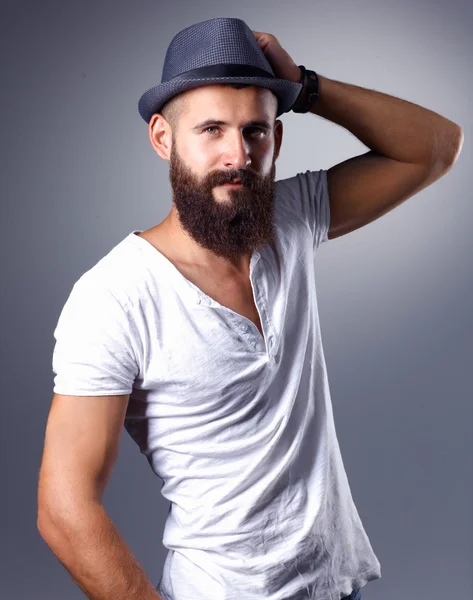 Retrato de homem barbudo bonito de chapéu em pé, isolado sobre fundo cinza — Fotografia de Stock