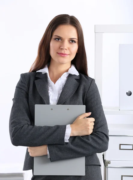 Atrakcyjna młoda bizneswoman stojąca przy biurku z folderem w biurze — Zdjęcie stockowe