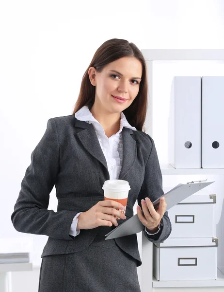 Atraktivní mladá podnikatelka stojící u stolu se složkou v kanceláři — Stock fotografie