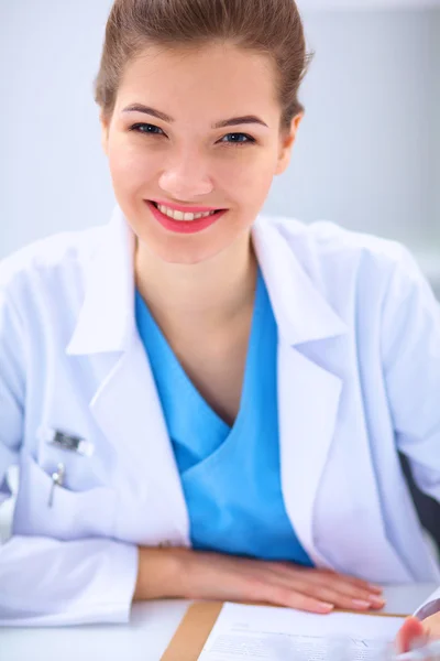 Belle jeune femme médecin souriante assise au bureau . — Photo