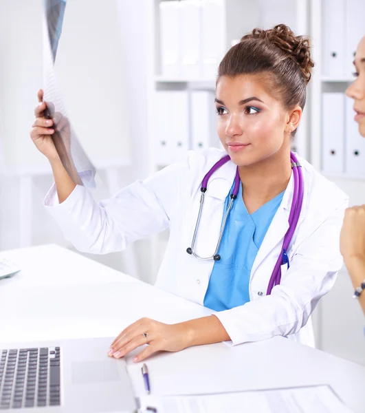 엑스레이 사진을 공부하는 젊은 여성 의사가 책상 위에 앉아 있는 모습 — 스톡 사진
