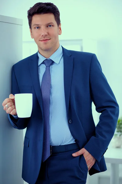一杯のコーヒーで立っている笑顔の実業家 — ストック写真