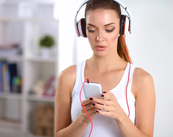 Mujer con auriculares escuchando música de pie en casa — Foto de Stock