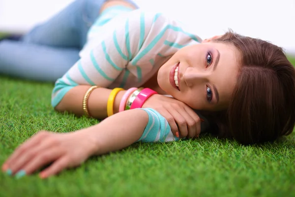 Mooie jonge vrouw liggend op groen gras — Stockfoto