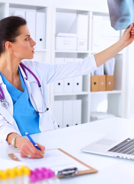 Young female doctor studying x-ray image sitting on the desk — Stock Photo, Image