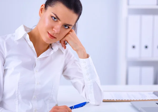 Aantrekkelijke zakenvrouw zit op een bureau met laptop in het kantoor — Stockfoto