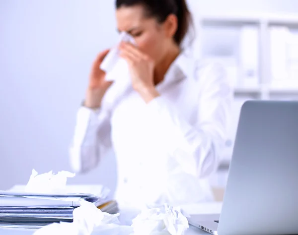 Junge Geschäftsfrau pustet sich die Nase, sitzt am Schreibtisch — Stockfoto