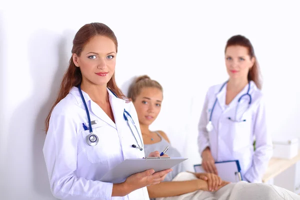 Médico sonriente con una carpeta en uniforme de pie en el hospital — Foto de Stock