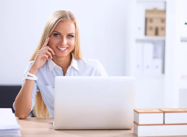 Aantrekkelijke zakenvrouw zit op een bureau met laptop in het kantoor — Stockfoto