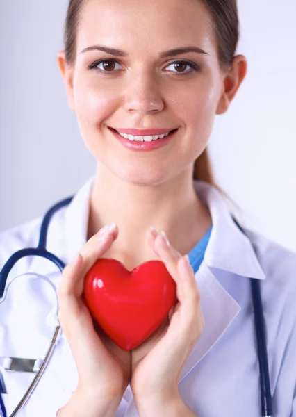 Mujer joven doctora sosteniendo un corazón rojo, aislado sobre fondo blanco —  Fotos de Stock