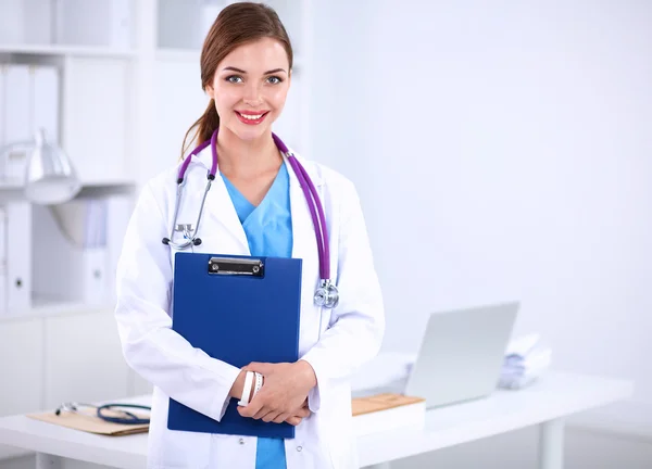 Lächelnde Ärztin mit Ordner in Uniform steht im Krankenhaus — Stockfoto