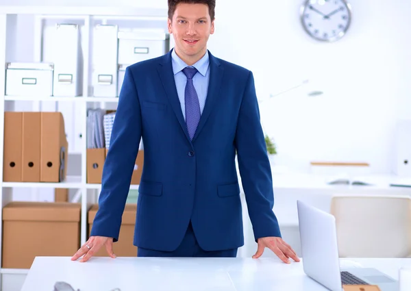 Vertrouwen succesvolle jonge zakenman leunend wapens op zijn Bureau — Stockfoto