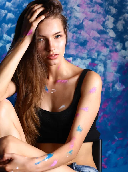 Young woman sitting near painting wall — Stock Photo, Image