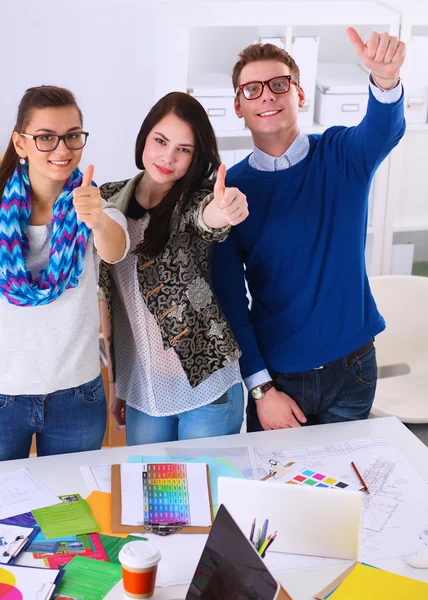 Young business people standing at office near desk and showing ok — Stock Photo, Image