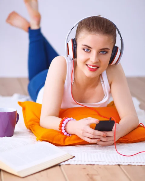 Mujer joven tumbada en el suelo y escuchando música — Foto de Stock