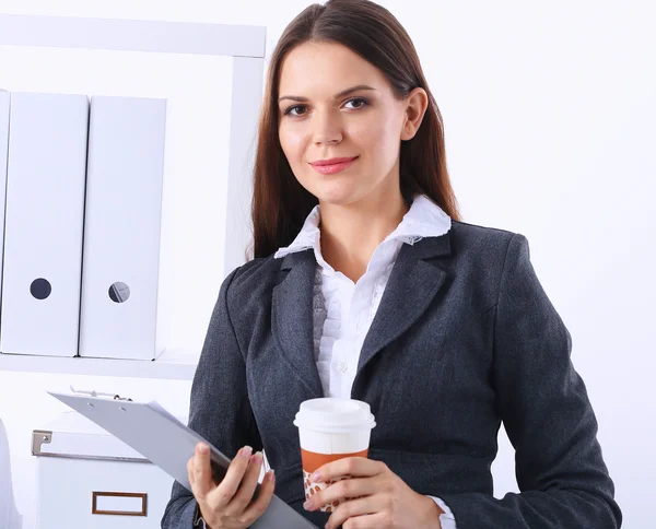 Empresaria con carpetas y taza de café, de pie en la oficina — Foto de Stock