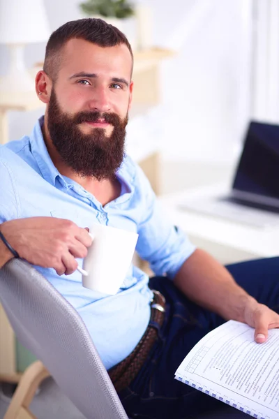 Young man sitting with laptop and a tea cup at home — Stock Photo, Image