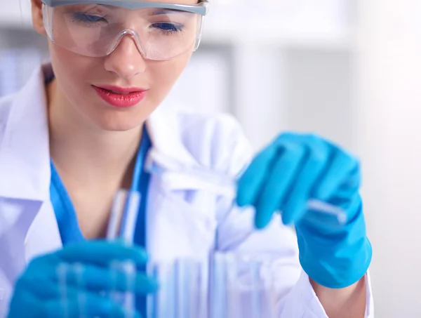 Woman researcher is surrounded by medical vials and flasks, isolated on white background — Stock Photo, Image