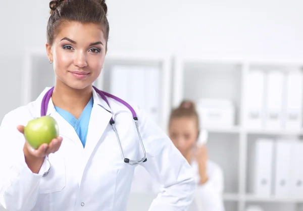महिला डॉक्टर हाथ में एक हरे सेब पकड़े हुए, खड़े — स्टॉक फ़ोटो, इमेज