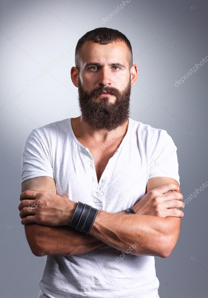 Portrait of handsome bearded man standing, isolated on grey background