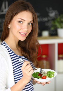 Salata yemek ve karışık salata tutan genç kadın 