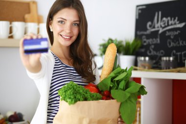 Kredi kartı ve evde mutfakta alışveriş çantası kadın ile