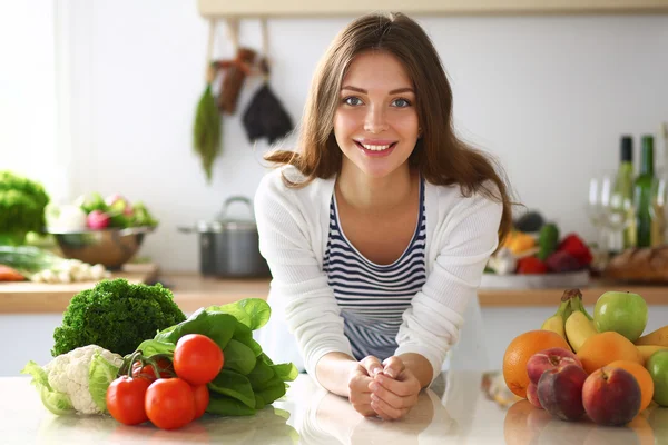 Jonge vrouw in de buurt van bureau in de keuken — Stockfoto