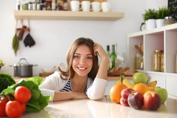 Jonge vrouw in de buurt van bureau in de keuken — Stockfoto