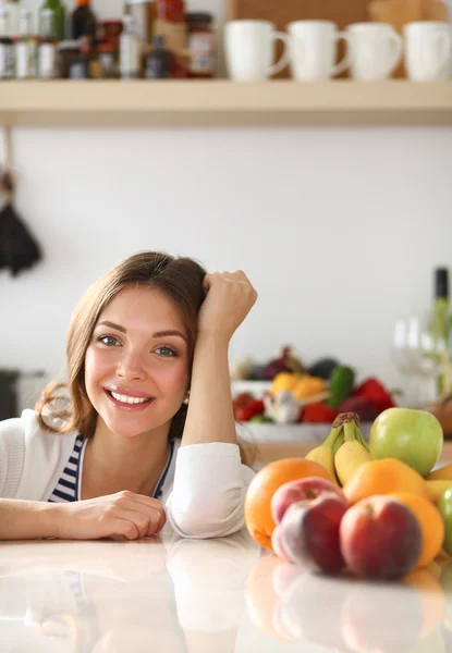 Jonge vrouw in de buurt van bureau in de keuken — Stockfoto