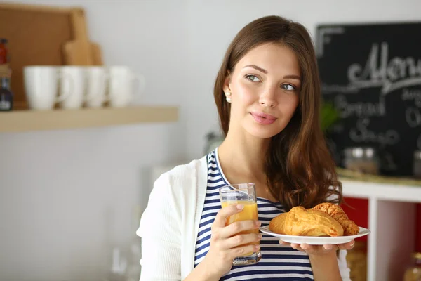 Ung kvinna med ett glas juice och kakor — Stockfoto