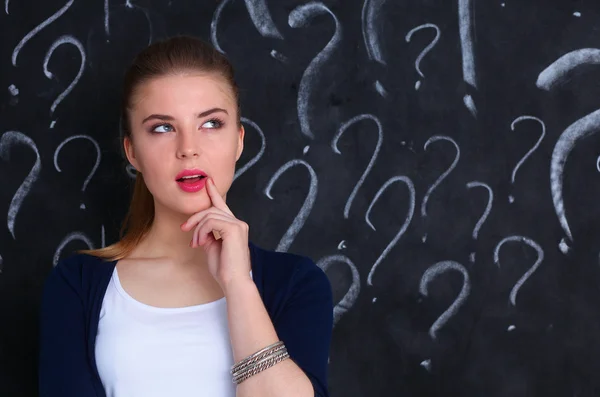 Junges Mädchen mit Fragezeichen auf grauem Hintergrund — Stockfoto