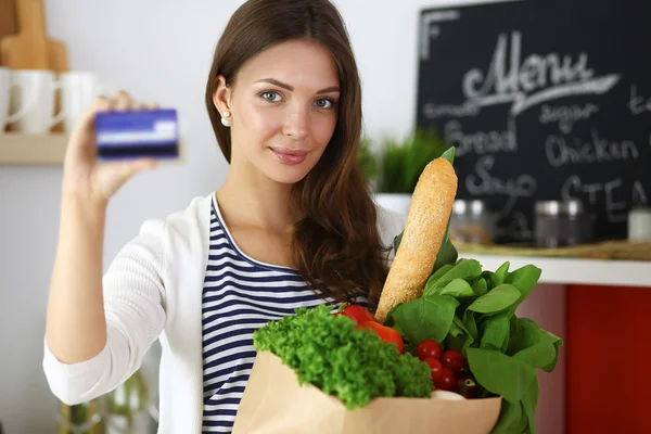 Frau mit Kreditkarte und Einkaufstasche zu Hause in der Küche — Stockfoto