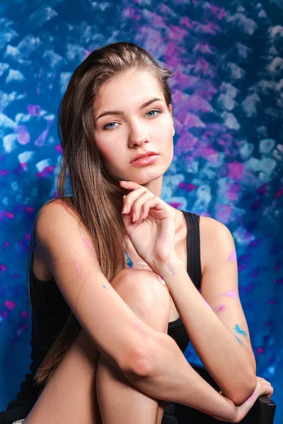 Young woman sitting near painting wall — Stock Photo, Image