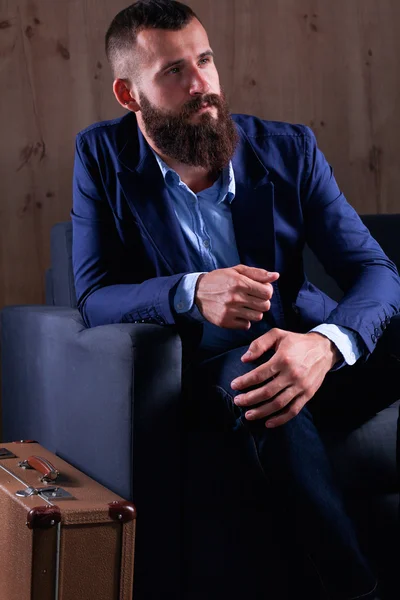 Businessman sitting the sofa in office lobby, isolated on dark background — Stock Photo, Image