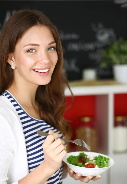 Junge Frau isst Salat und hält einen gemischten Salat in der Hand — Stockfoto