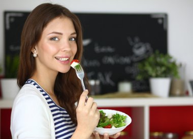 Salata yemek ve karışık salata tutan genç kadın 