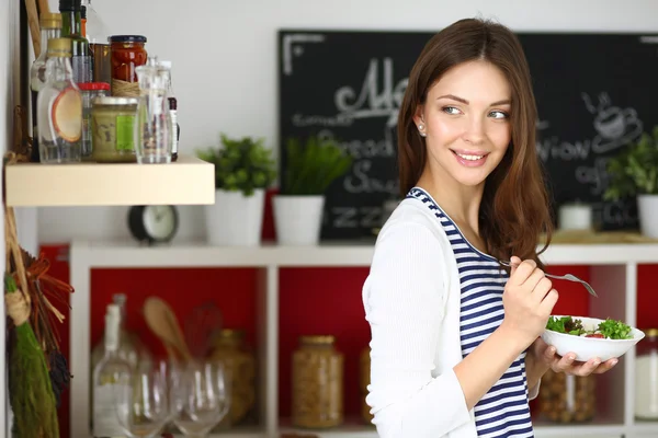 Mujer joven comiendo ensalada y sosteniendo una ensalada mixta —  Fotos de Stock