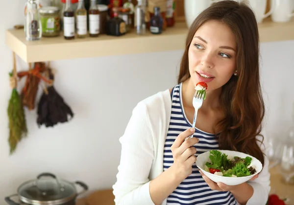 Ung kvinna äta sallad och hålla en blandad sallad — Stockfoto