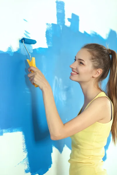 Güzel genç bir kadın duvar boyuyor. — Stok fotoğraf