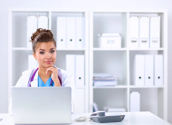 Médica mulher sentada na mesa e trabalhando em um laptop no hospital — Fotografia de Stock
