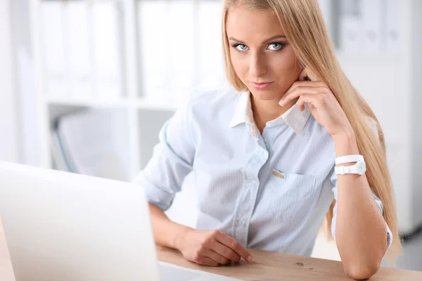 Aantrekkelijke zakenvrouw zit op een bureau met laptop in het kantoor — Stockfoto