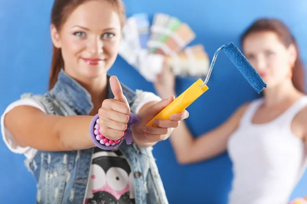 Två unga vackra kvinnor hålla färgpalett, står nära vägg. — Stockfoto