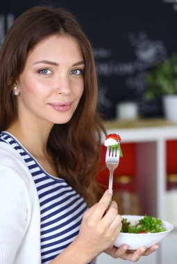 Salata yemek ve karışık salata tutan genç kadın 