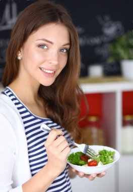 Salata yemek ve karışık salata tutan genç kadın 
