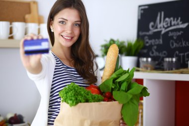 Kredi kartı ve evde mutfakta alışveriş çantası kadın ile