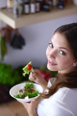 Salata yemek ve karışık salata tutan genç kadın 