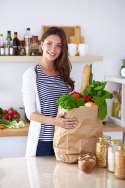 Genç bir kadın mutfakta duruyor.