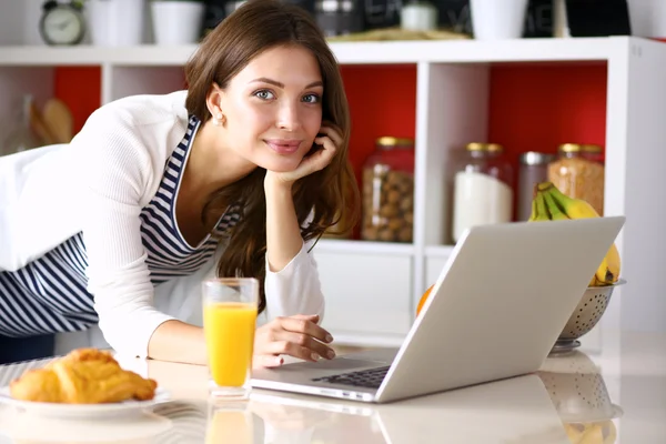 Привлекательная молодая женщина с ноутбуком и сидя на кухне — стоковое фото