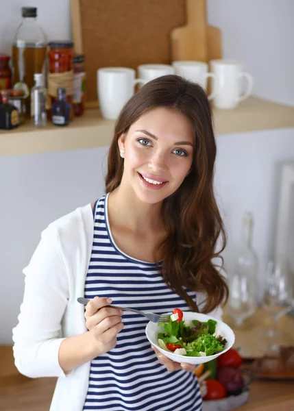 Salata yemek ve karışık salata tutan genç kadın 