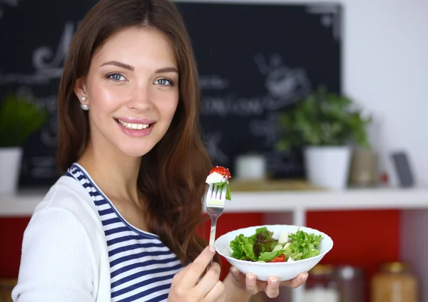 Mujer joven comiendo ensalada y sosteniendo una ensalada mixta — Foto de Stock